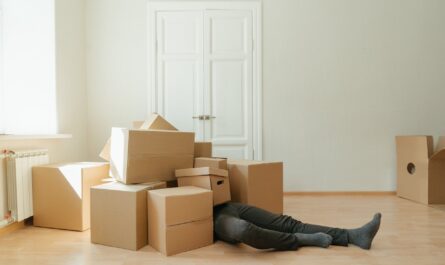 person in black leather boots lying on brown cardboard boxes
